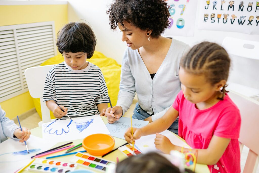 Children and teacher engaged in a creative painting session in a classroom setting.